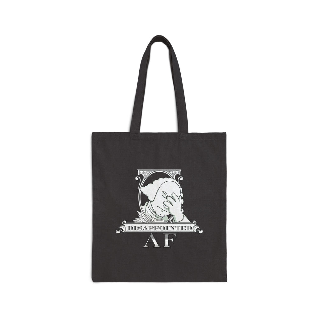 A black canvas tote bag with two black shoulder straps, featuring a white version of the Disappointed AF logo.  The logo for Disappointed AF is framed with scrolls, similar to that of a dollar bill, with George Washington in the center. George Washington looks disappointed and has his head in his hand. below the logo it says Disappointed AF.