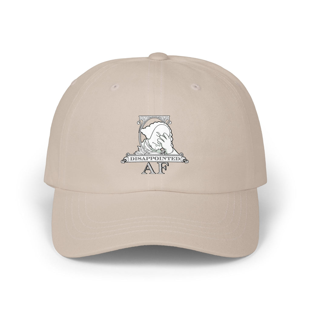 A beige baseball cap with a white graphic on the front depicting Disappointed AF's logo. The logo is framed with scrolls, similar to that of a dollar bill, with George Washington in the center. George Washington looks disappointed and has his head in his hand.