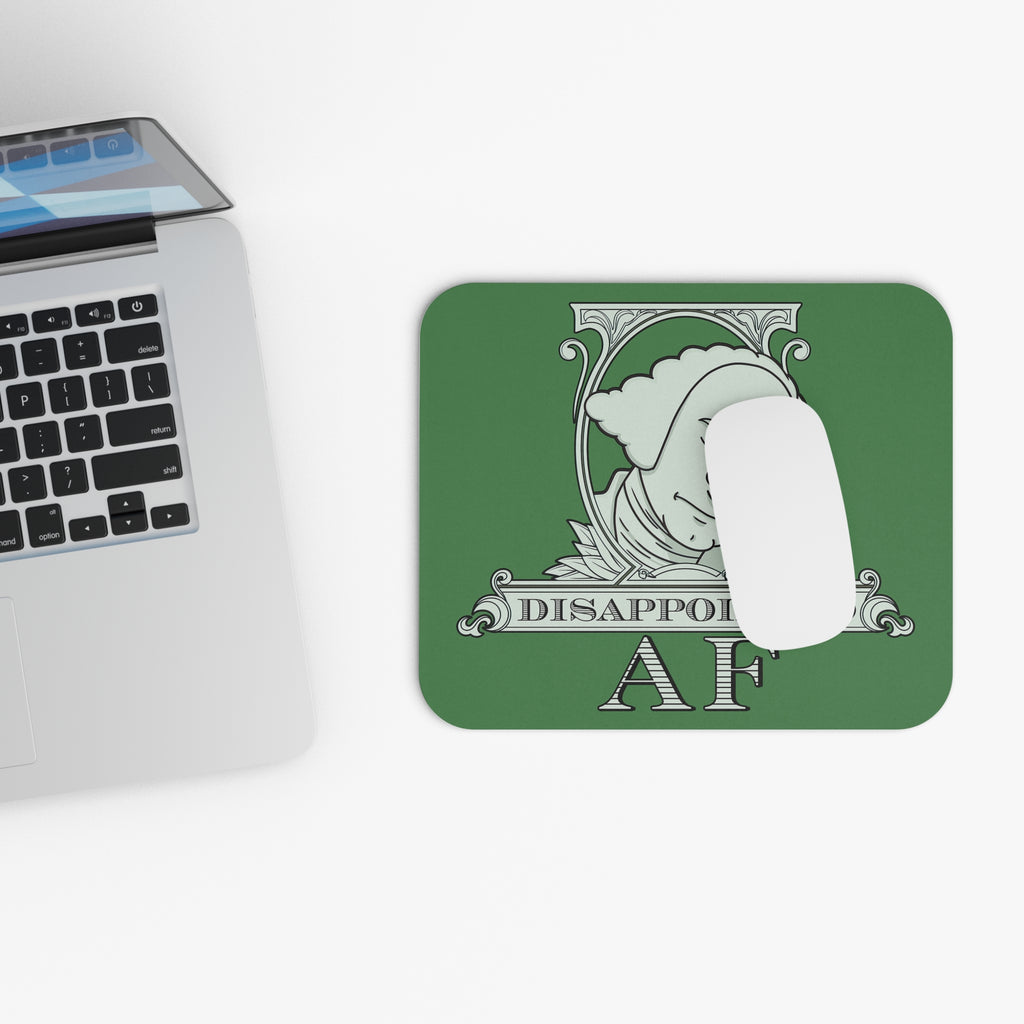 A square green mousepad with a mouse on top of it, all on a white background with rounded corners featuring a logo in the center. This is the logo for Disappointed AF and is framed with scrolls, similar to that of a dollar bill, with George Washington in the center. George Washington looks disappointed, is leaning his head forward, and has his head in his hand with an exasperated look on his face. Below the figure it says Disappointed AF. A laptop computer is partially in view on the left side of the frame