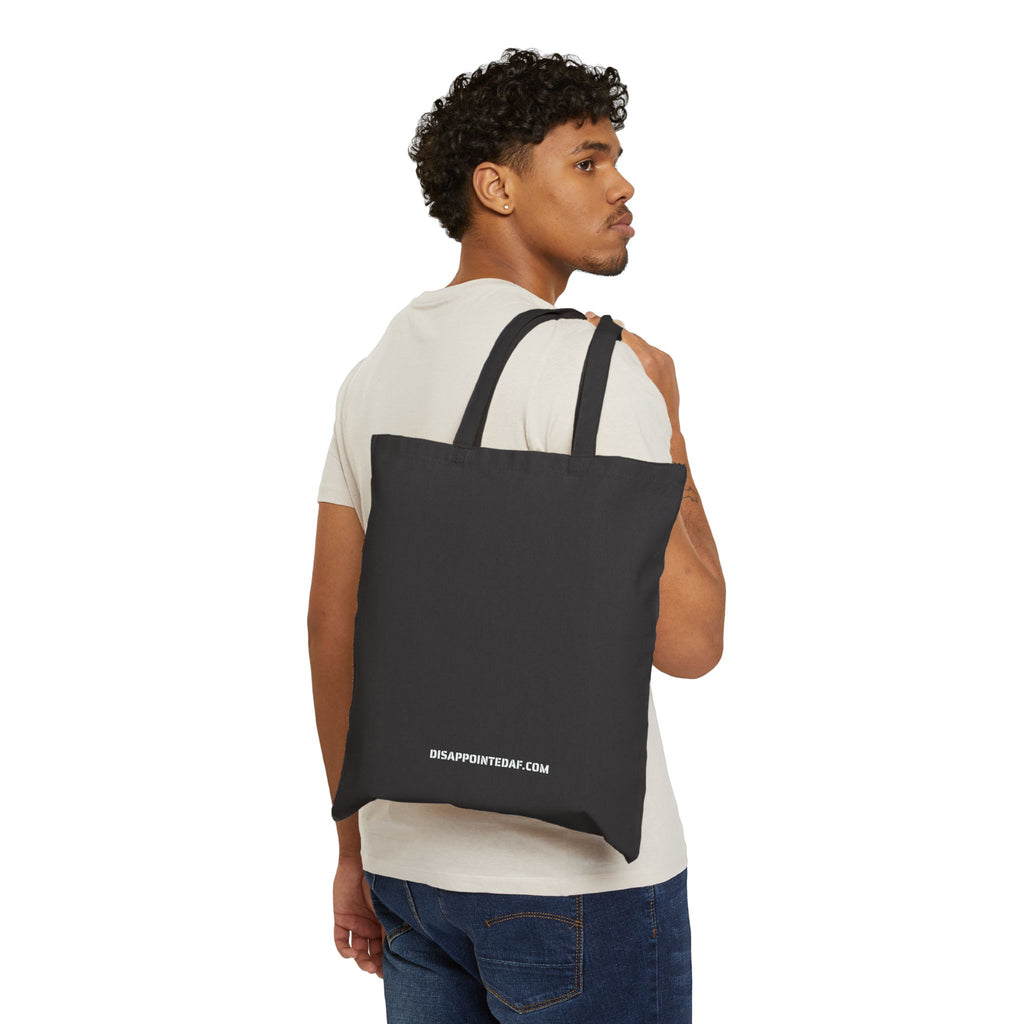 Man carrying a black tote bag on a white background. At the bottom of the tote bag, the URL DisappointedAF.com is printed in white ink.