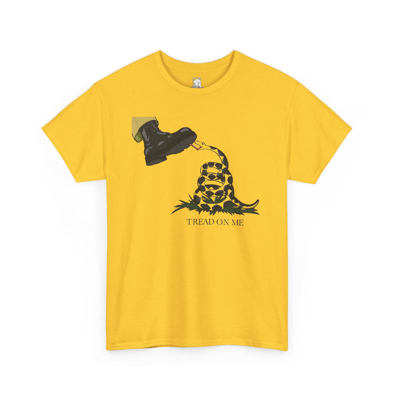 A yellow short-sleeve crewneck t-shirt featuring a graphical parody of the classic "Don't Tread on Me" cartoon. In this rendition, a boot enters the frame in the upper left hand corner, its sole exposed to the viewer. Beneath the boot is a snake, coiled up and licking the bottom of the boot. The graphic is captioned by the words 'TREAD ON ME' underneath, displayed on a clean white background.