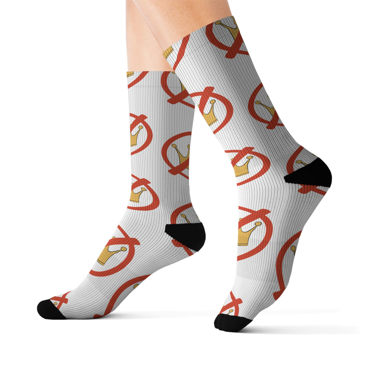 A pair of crew socks worn on legs, featuring a white ribbed base with a repeating graphic of a gold crown inside a red prohibition symbol, finished with black heels and toes.