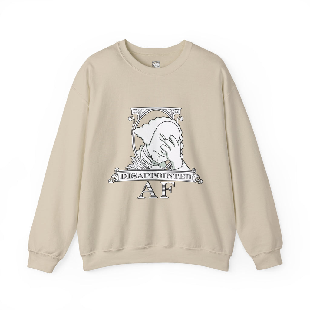A beige, long-sleeved sweatshirt with a graphic in the center on a white background. This graphic is the logo for Disappointed AF and is framed with scrolls, similar to that of a dollar bill, with George Washington in the center. George Washington looks disappointed and has his head in his hand. below the logo it says Disappointed AF